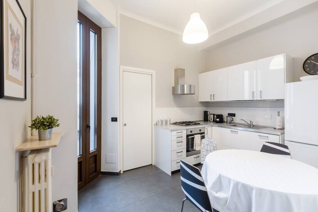 Une cuisine moderne avec des meubles blancs, une cuisinière à gaz et un coin repas comprenant une table et des chaises.