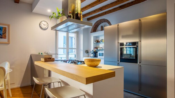 A modern kitchen with a wooden island, stainless steel appliances, and a large window. - Easylife - Splendid penthouse in Porta Venezia (Milano)