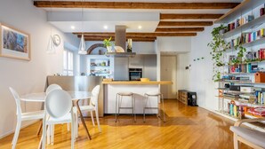 A modern kitchen with wooden beams, a central island, and bar stools. - Easylife - Splendid penthouse in Porta Venezia (Milano)