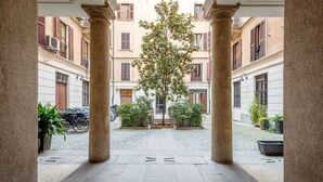 A courtyard with a central tree, surrounded by buildings with balconies and shutters. - Easylife - Splendid penthouse in Porta Venezia (Milano)