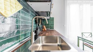 A modern kitchen with a stainless steel sink, green tiled backsplash, and wooden countertop.
