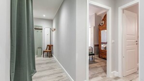 A hallway with a wooden floor, a green curtain, and a wooden chair.