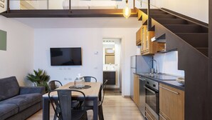 Un appartement moderne comprenant un coin repas, une cuisine et un escalier.