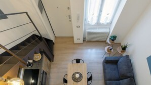 Un appartement moderne doté d’un escalier, d’un coin repas, d’un canapé et offrant une vue sur l’extérieur.