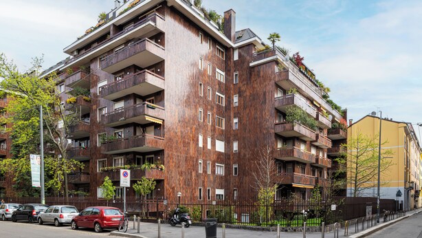 Um edifício residencial com vários andares, varandas, uma faixa de pedestres e carros estacionados.