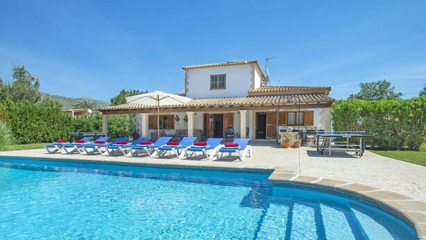 Un espace aménagé au bord de la piscine, avec des chaises longues, et une maison en arrière-plan.