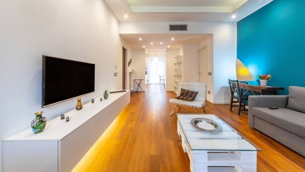 A modern living room with a flat-screen TV, a coffee table, and a sofa. - Easylife - Luxurious two-room apartment with balcony and hot tub in the Barona (Milano)
