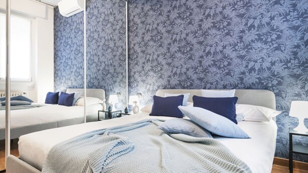 Een slaapkamer met een groot bed, een nachtkastje, een spiegel en een raam.