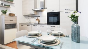 Een moderne keuken met witte kasten, een roestvrijstalen afzuigkap en een zwarte oven.