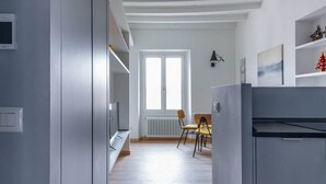 Una cocina moderna con horno empotrado, una zona de comedor con mesa y sillas, y un amplio ventanal que proporciona luz natural.