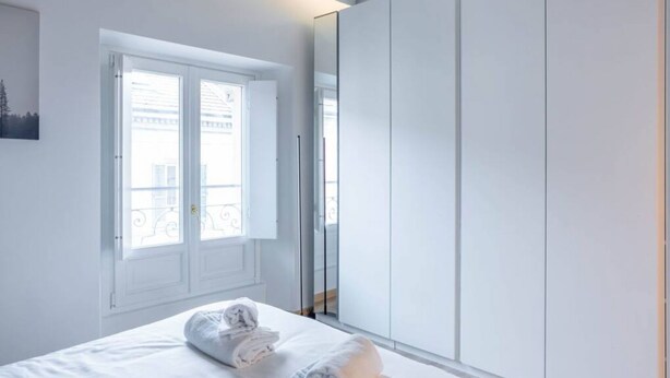 Un dormitorio con cama, ventana y armario.