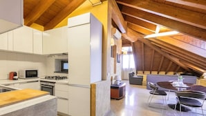 Une cuisine moderne avec des meubles blancs, un four à micro-ondes, une cuisinière et un coin repas comprenant une table et des chaises.