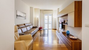 Un salon moderne avec un canapé en cuir, une table basse en bois et un téléviseur posé sur un meuble en bois.