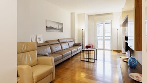 Un salon moderne avec un canapé en cuir beige, une petite table basse noire et un plancher en bois.