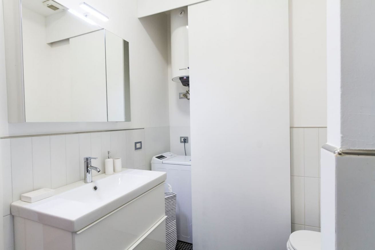Une salle de bain moderne avec un lavabo blanc, un miroir et un lave-linge.