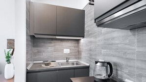 Une cuisine moderne avec des meubles de couleur grise, un évier en acier inoxydable et une machine à café posée sur le plan de travail.