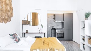 Une chambre d’hôtel moderne équipée d’un lit, d’une table de chevet, d’un miroir et donnant sur la cuisine.