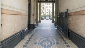 Un corridoio con pavimento piastrellato, colonne e un cancello in metallo.