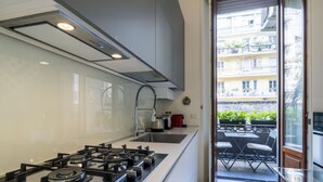 Una cucina moderna con piano cottura a gas, lavandino e finestra vista balcone con mobili da esterno.