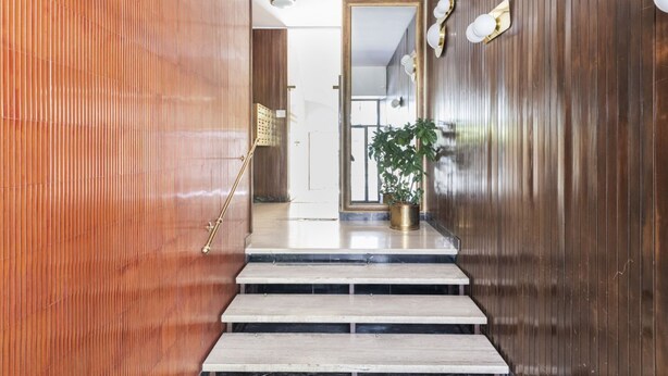 Una escalera conduce a una habitación con paneles de madera y una planta en maceta.