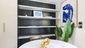Un comedor moderno con una mesa de mármol, una cesta de frutas y una planta verde grande.