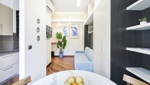 Una cocina moderna con armarios blancos, una silla de madera y una cesta de frutas sobre la mesa de comedor.