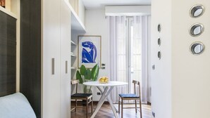 Una sala moderna con un sofá azul, una mesa de comedor con sillas y una planta grande.