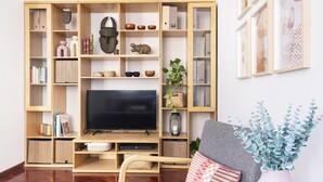 Una sala de estar con televisor, estanterías de madera y un sofá.