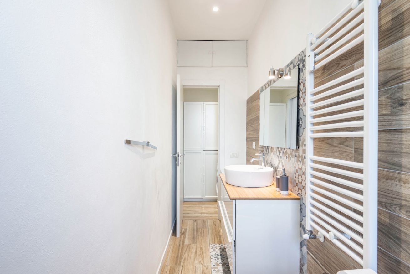 Une salle de bain moderne avec un meuble-lavabo en bois, un lavabo blanc et un grand miroir.
