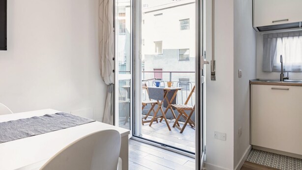 Ein Zimmer mit einer Schiebetür zu einem Balkon im Freien, ausgestattet mit Tisch und Stühlen.