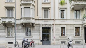 Un bâtiment historique à la façade classique, doté d’une entrée centrale et où sont garées deux motos.