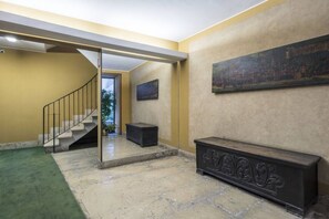 A staircase leading to an upper floor, a bench, and a painting on the wall.