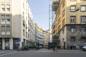 A street view with buildings, a pedestrian crossing, and parked scooters.