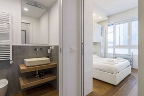 A modern bathroom with a large mirror, a white sink, and a toilet.