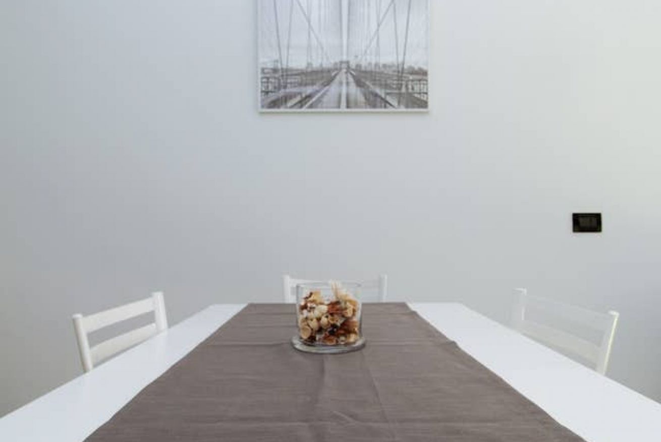 A dining table with a dark tablecloth, white chairs, and a centerpiece of dried flowers.