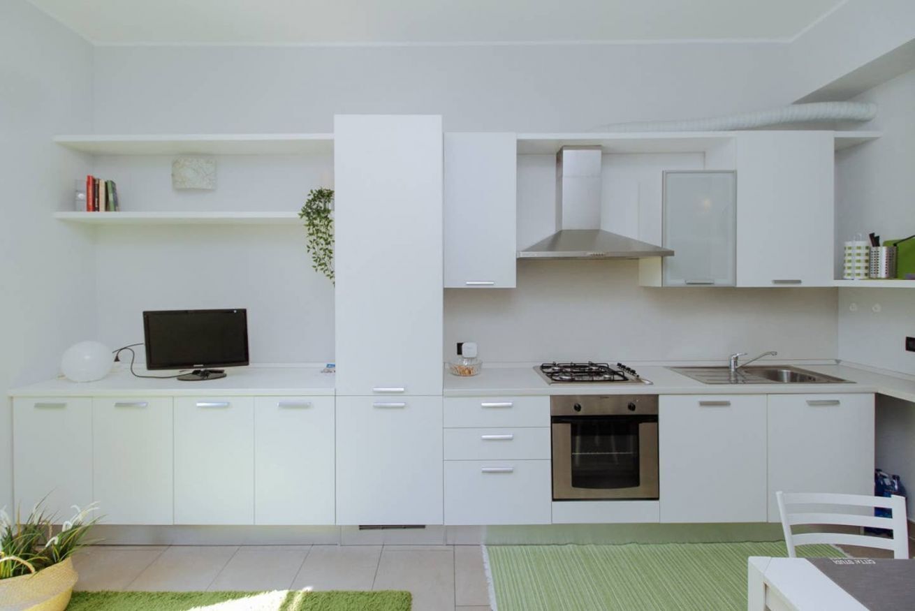 Een moderne keuken met witte kasten, een gasfornuis, een inbouwoven en een spoelbak.