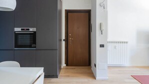 A modern kitchen with dark cabinetry, a built-in oven, and a wooden door.