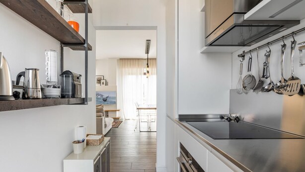 A modern kitchen with stainless steel appliances, wooden flooring, and a view to the dining area. - Easylife - Comfort in Pta Romana with terrace (Milano)