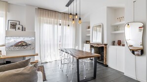 A modern living room with a wooden dining table, clear chairs, a fireplace, and a large mirror. - Easylife - Comfort in Pta Romana with terrace (Milano)