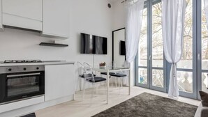 A modern kitchen with a built-in oven, a dining area with clear chairs, and a large sliding glass door to the outdoors.