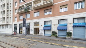 Ein mehrstöckiges Gebäude mit Geschäften im Erdgeschoss, darunter eine Pizzeria und ein Restaurant.