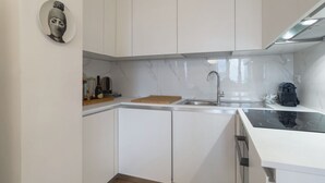 Eine moderne Küche mit weißen Schränken, einer Marmor-Spritzschutzleiste, einem eingebauten Backofen und einer Edelstahl-Spüle.