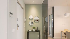 A modern hallway with a glass door, a console table with decorative items, and three wall-mounted mirrors. - Easylife - Precious Pearl in Porta Romana (Milano)