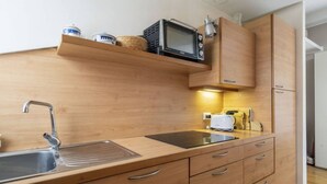 A modern kitchen with wooden cabinets, a built-in microwave, and a toaster. - Easylife - Cozy studio apartment in Navigli area (Milano)