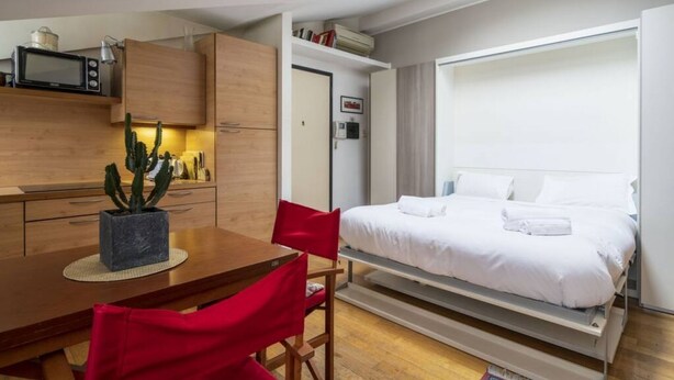 A compact room with a bed, a small kitchenette, and a dining area. - Easylife - Cozy studio apartment in Navigli area (Milano)