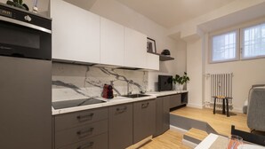 Une cuisine moderne avec des meubles gris, un pare-feu en marbre et un four encastré.