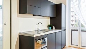 A modern kitchen with dark cabinets, a stainless steel sink, and a built-in oven. - Easylife - Design and new flat in Navigli district (Milano)