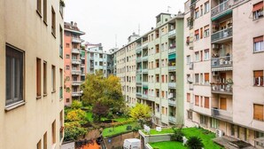 A multi-story residential building with balconies, a small courtyard, and a green lawn. - Easylife - Design and new flat in Navigli district (Milano)