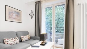 A modern living room with a grey sofa, patterned cushions, a white coffee table, and a framed artwork on the wall. - Easylife - Bright and charming flat with balcony (Milano)