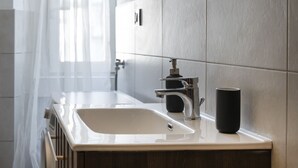 A modern bathroom with a white sink, a black cup, and a towel rack.